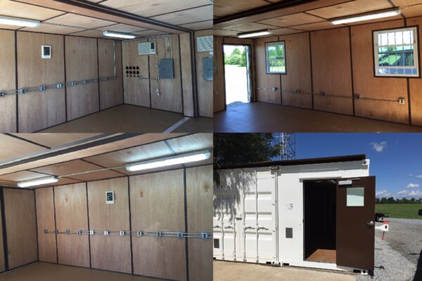 A custom shipping/storage container showing bare wooden walls, electical outlets, windows, and an air conditioning unit located on the wall next to an electrical breaker box designed for military use.